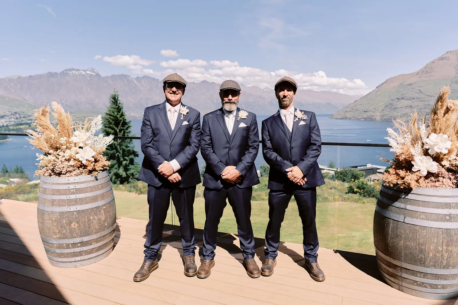 Queenstown Elopement Heli Wedding Photographer クイーンズタウン結婚式 | Three groomsmen standing in front of barrels with mountains in the background at the Kamana Lakehouse Queenstown Elopement.
