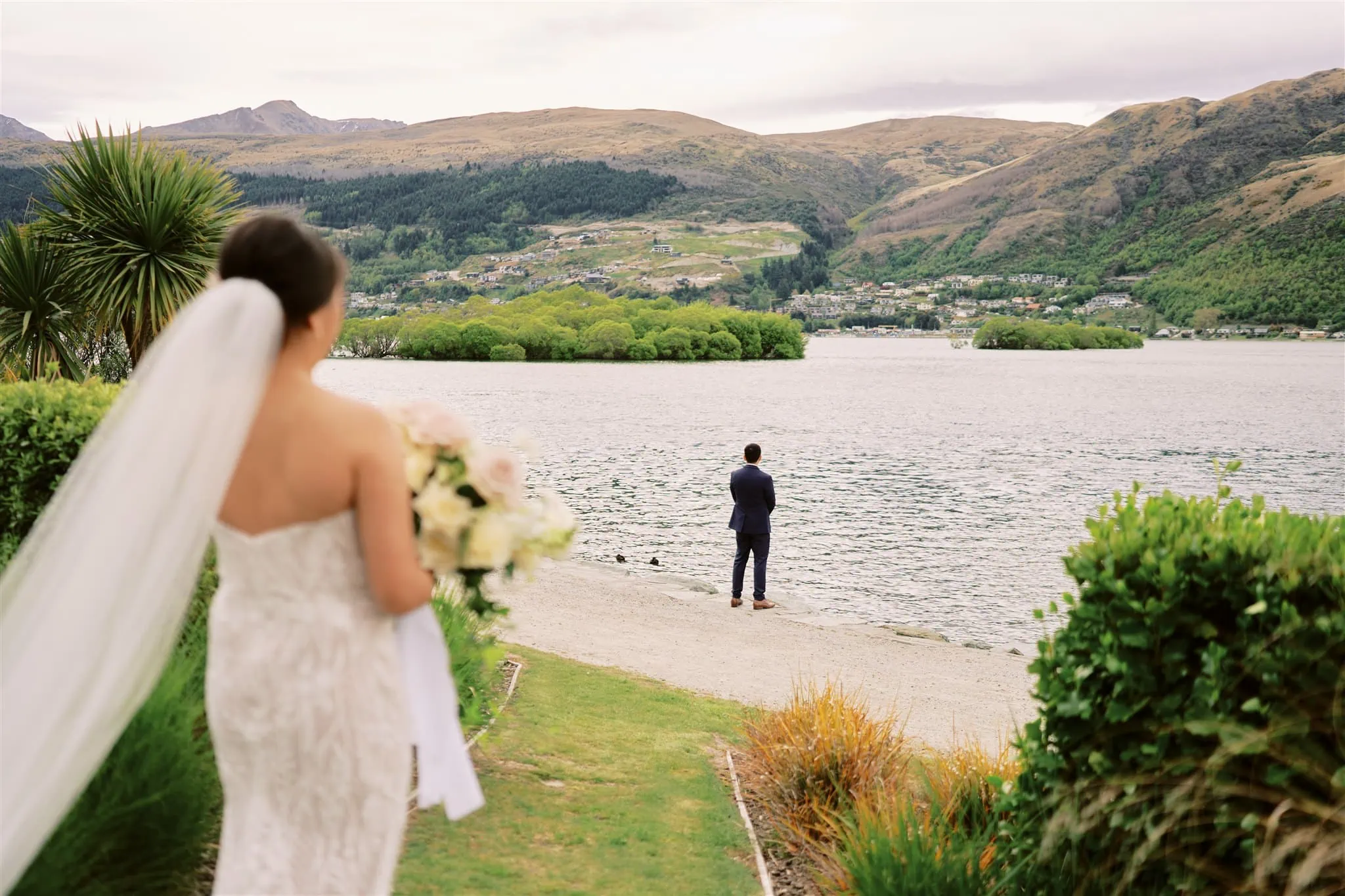 Queenstown Elopement Heli Wedding Photographer クイーンズタウン結婚式 | A bride and groom standing on the shore of Lake Wanaka near Queenstown.