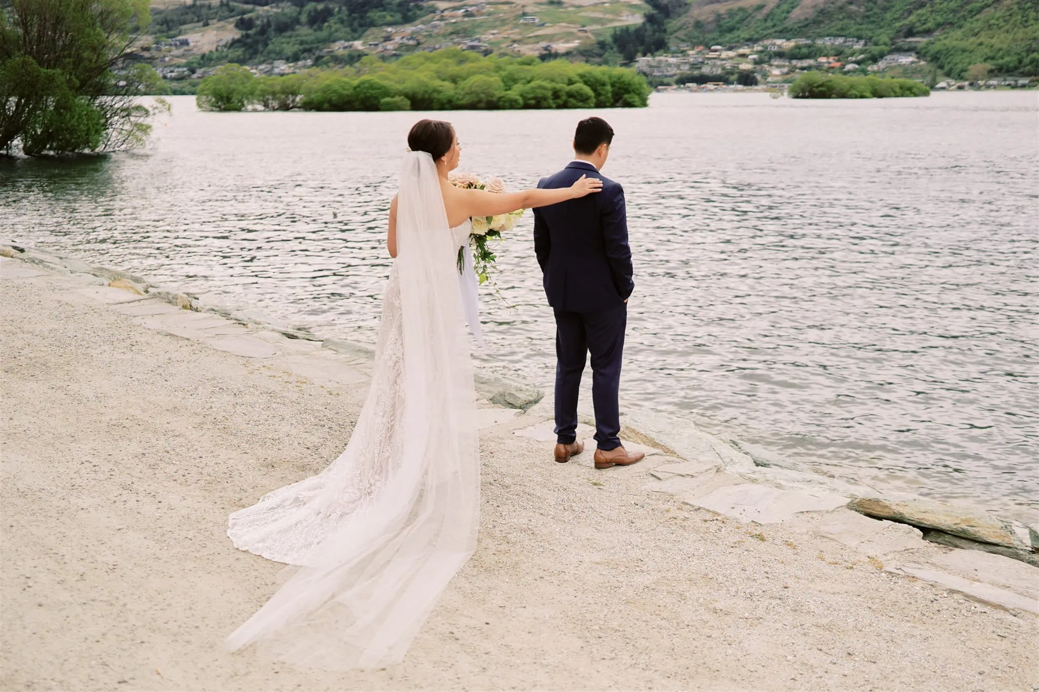 Queenstown Elopement Heli Wedding Photographer クイーンズタウン結婚式 | Cliff & Mariah's epic Queenstown elopement captured the stunning moment of a woman in a white dress holding a man in a suit.