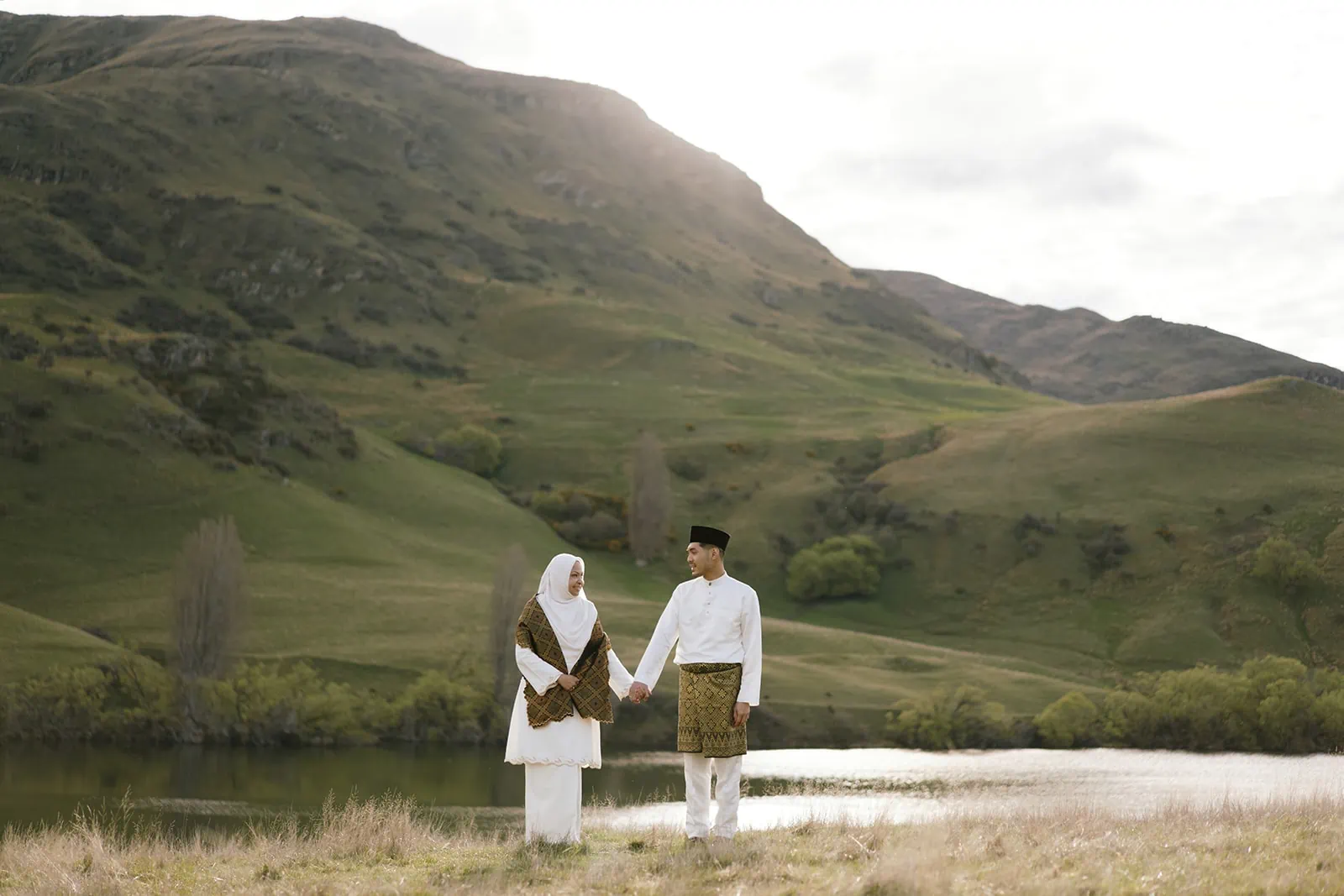 Queenstown Elopement Heli Wedding Photographer クイーンズタウン結婚式 | A Muslim couple holding hands in front of a breathtaking lake during their Queenstown wedding.