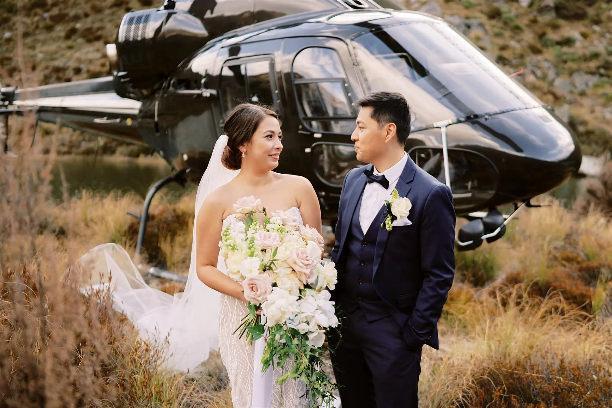 Queenstown Elopement Heli Wedding Photographer クイーンズタウン結婚式 | A bride and groom eloping in Queenstown, standing in front of a helicopter.