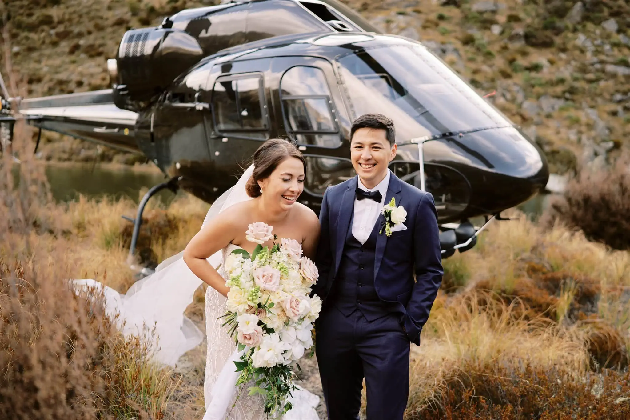 Queenstown Elopement Heli Wedding Photographer クイーンズタウン結婚式 | A bride and groom, Mariah and Cliff, standing in front of a helicopter in Queenstown.