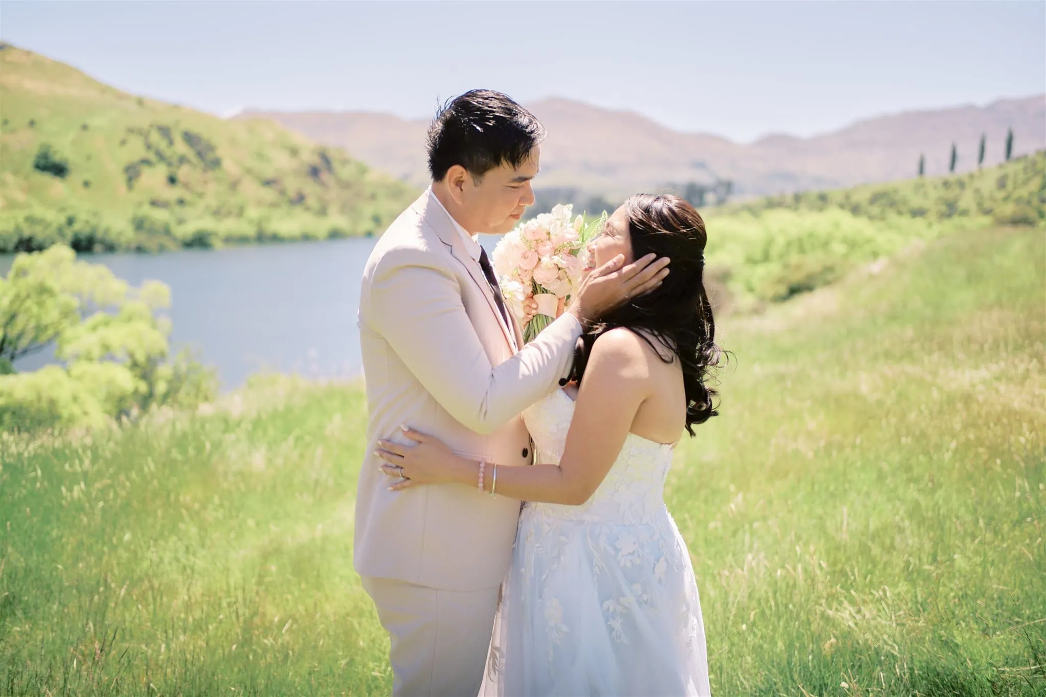 Queenstown Elopement Heli Wedding Photographer クイーンズタウン結婚式 | A Queenstown elopement - a bride and groom kissing in front of a lake.