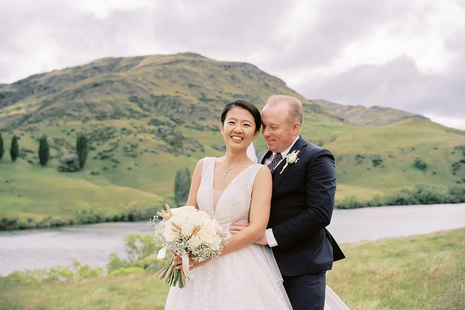 Queenstown Elopement Heli Wedding Photographer クイーンズタウン結婚式 | Meng and Joel, a bride and groom, posing in front of a lake at their Stoneridge Estate Wedding.