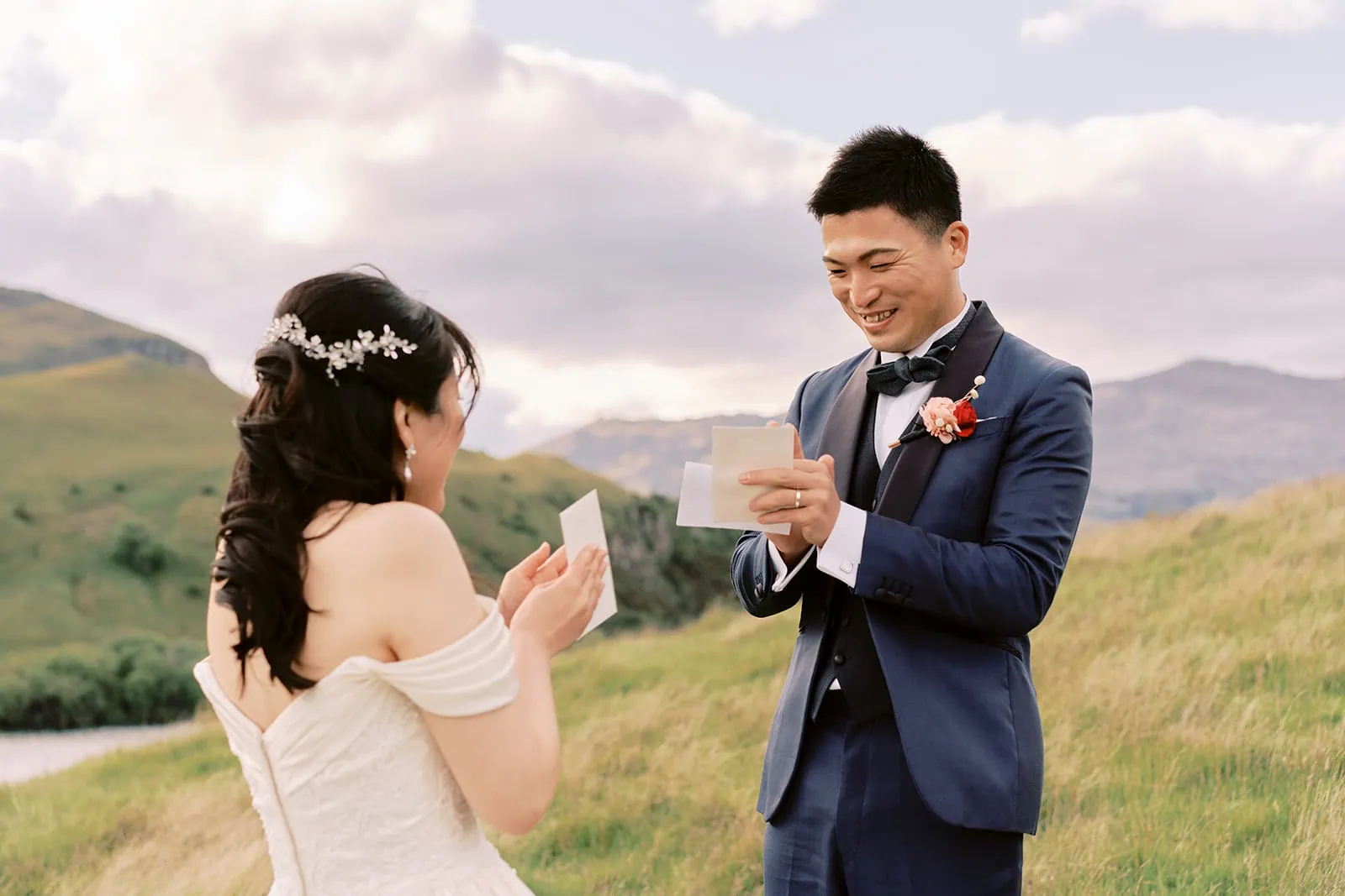 Queenstown Elopement Heli Wedding Photographer クイーンズタウン結婚式 | A bride and groom having a pre-wedding photoshoot in a field with mountains in the background.