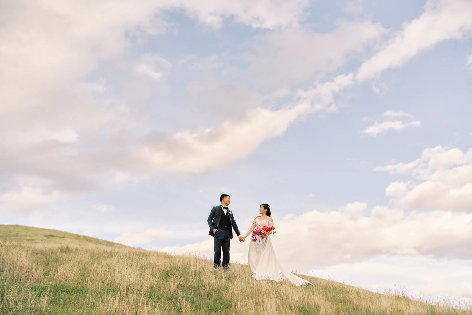 Queenstown Elopement Heli Wedding Photographer クイーンズタウン結婚式 | A couple embracing during their pre-wedding photoshoot on top of a grassy hill.