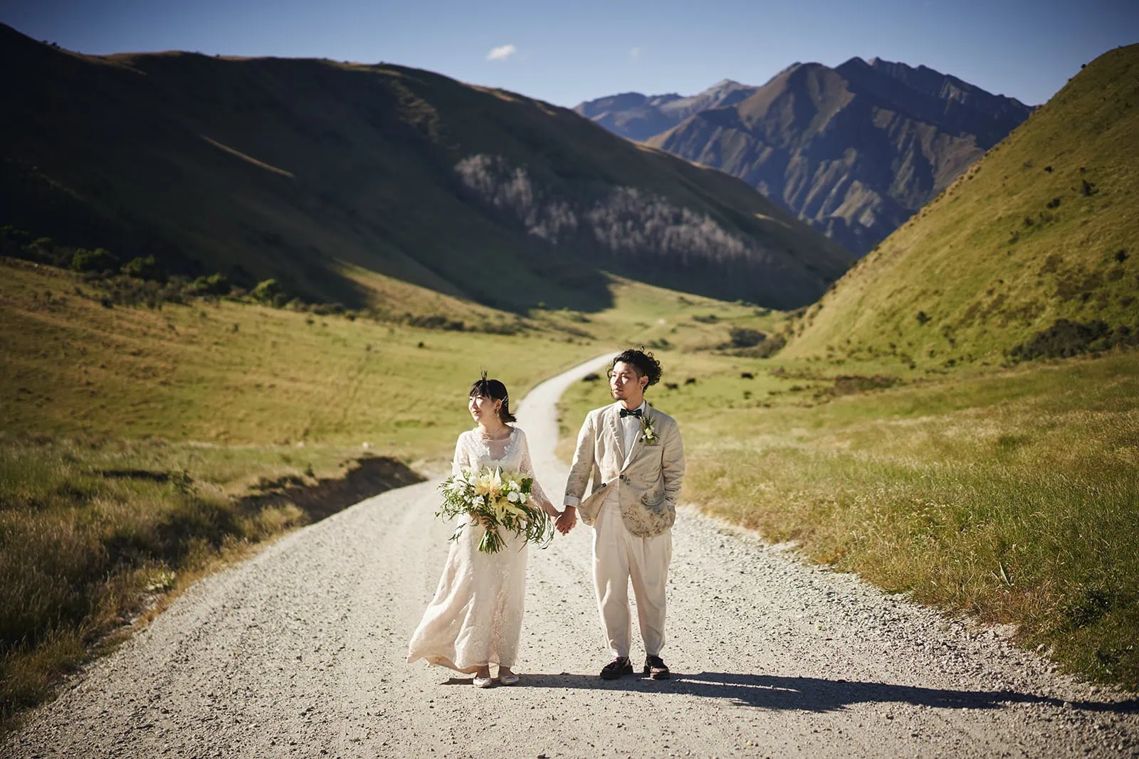 Queenstown Elopement Heli Wedding Photographer クイーンズタウン結婚式 | Eriko & Naoki, a bride and groom, captured their Queenstown Heli Pre-Wedding Shoot while walking down a dirt road in the mountains.