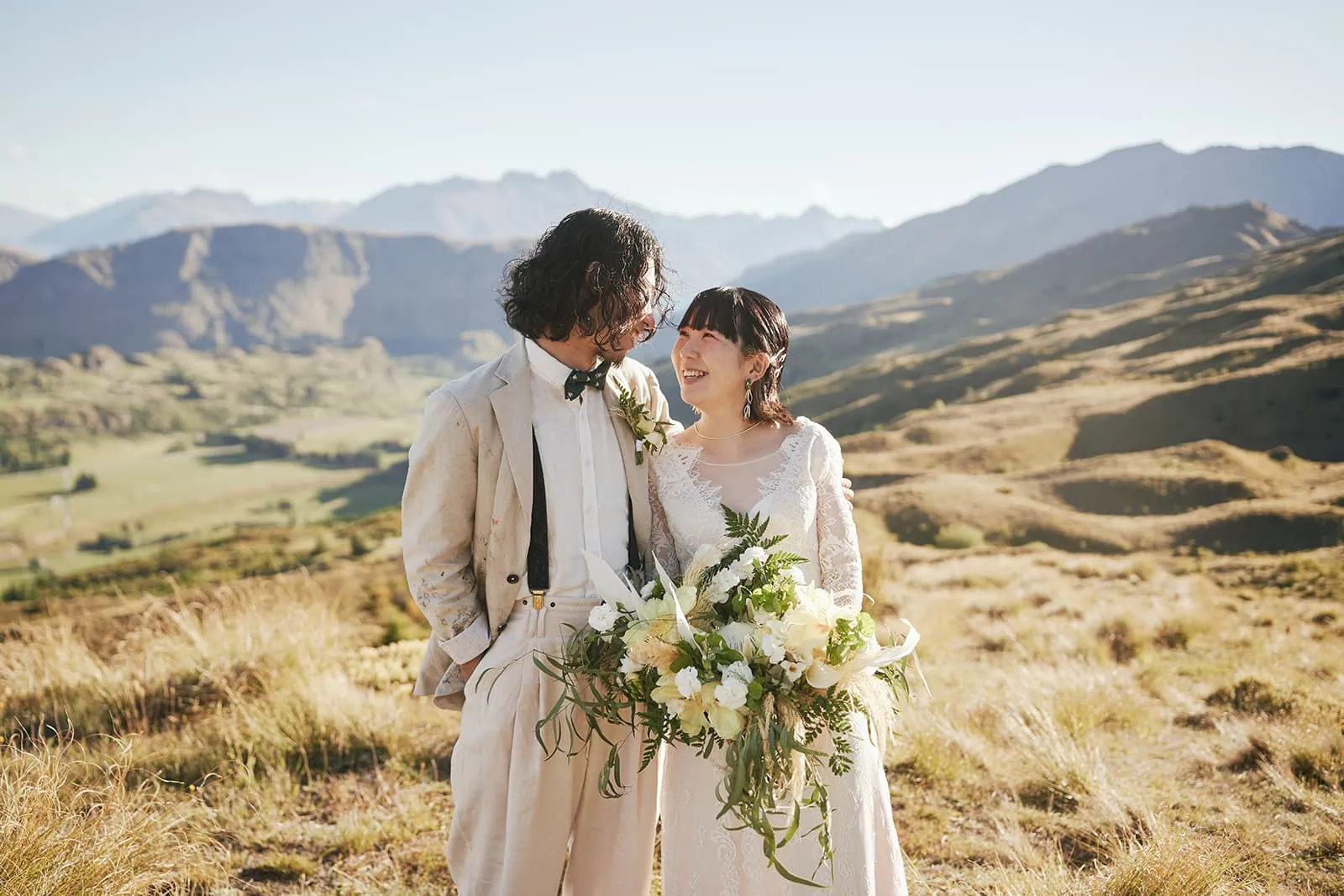 Queenstown Elopement Heli Wedding Photographer クイーンズタウン結婚式 | A Pre-Wedding couple standing on top of a hill in Queenstown, with majestic mountains in the background.