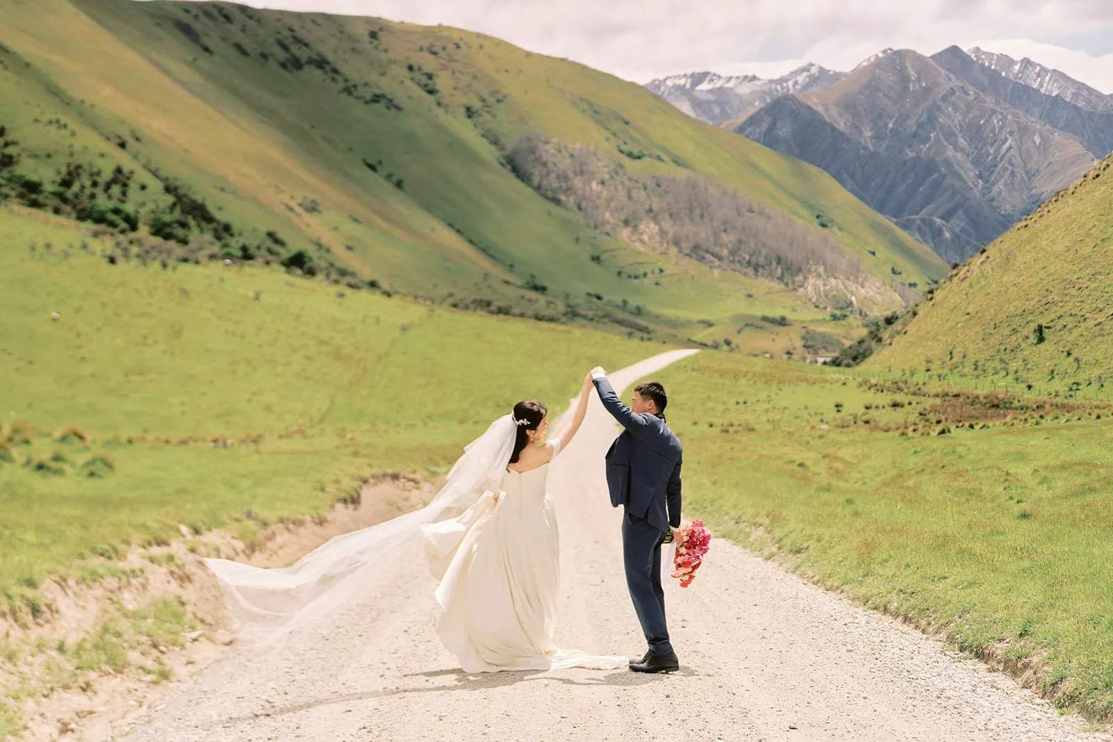 Queenstown Elopement Heli Wedding Photographer クイーンズタウン結婚式 | A bride and groom having their pre-wedding photoshoot on a dirt road in the mountains.