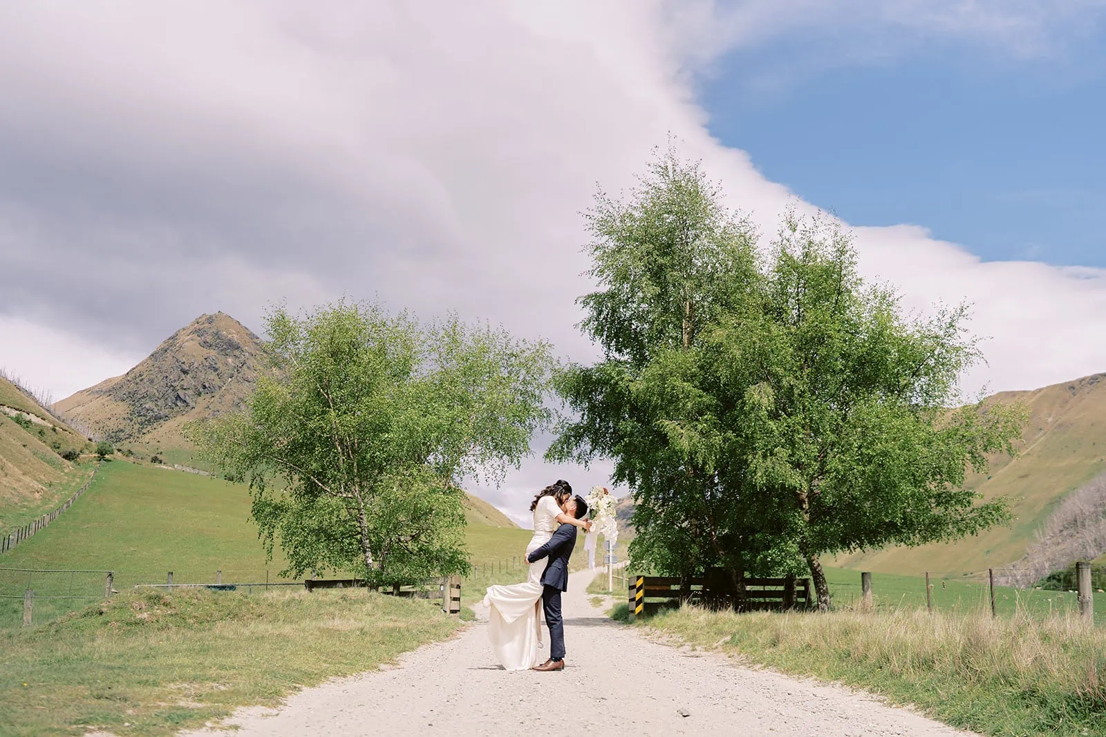 Queenstown Elopement Heli Wedding Photographer クイーンズタウン結婚式 | A couple passionately kissing on a dirt road during their pre-wedding photoshoot.