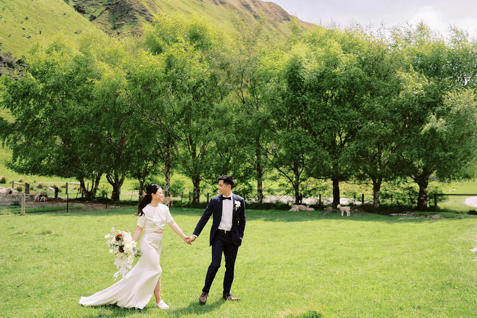 Queenstown Elopement Heli Wedding Photographer クイーンズタウン結婚式 | A pre-wedding photoshoot of a bride and groom standing in a field with mountains in the background.