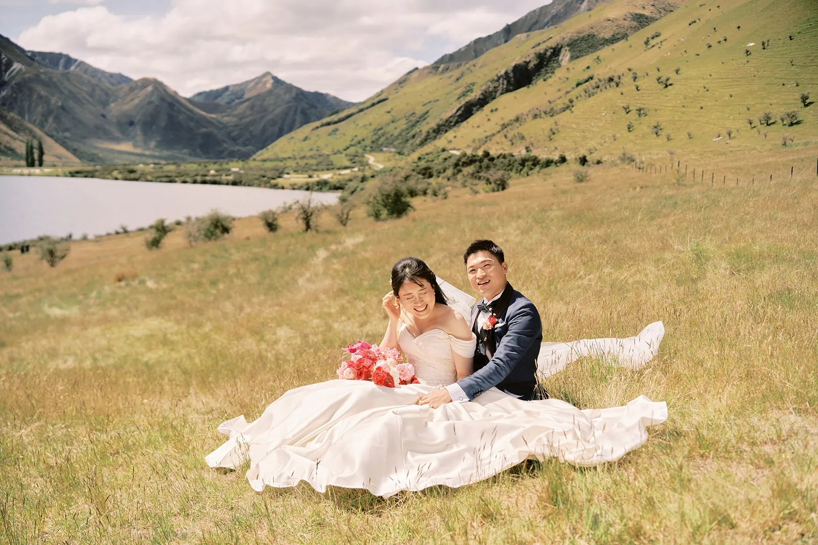 Queenstown Elopement Heli Wedding Photographer クイーンズタウン結婚式 | A couple enjoying a pre-wedding photoshoot in a picturesque field, with stunning mountains forming the mesmerizing backdrop.