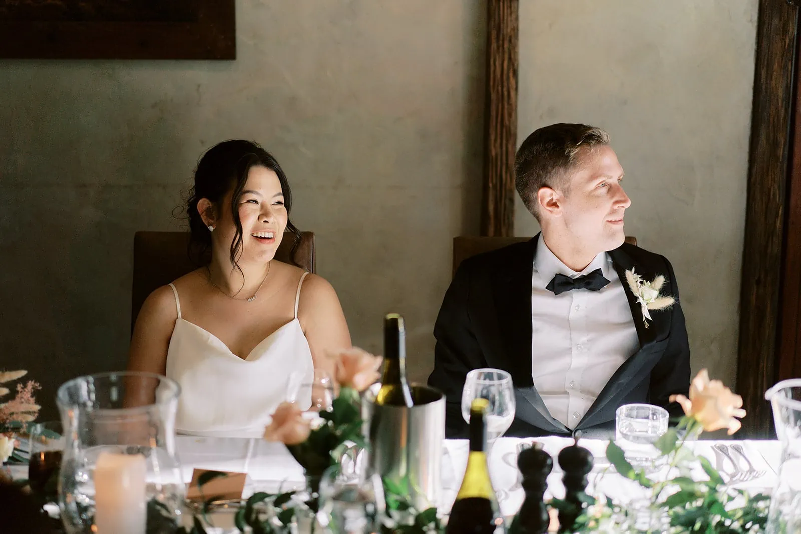 Queenstown Elopement Heli Wedding Photographer クイーンズタウン結婚式 | A bride and groom, Mj & Shane, exchanging smiles at their Wedding reception table at Stoneridge Queenstown.