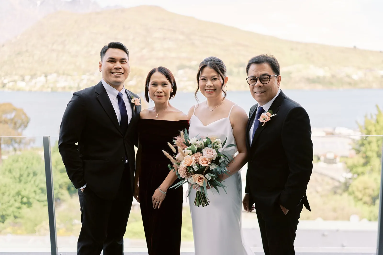 Queenstown Elopement Heli Wedding Photographer クイーンズタウン結婚式 | A group of people, including Stoneridge and Shane, posing for a photo on a balcony overlooking a lake.