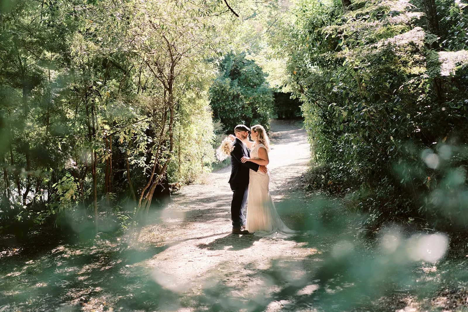 Queenstown Elopement Heli Wedding Photographer クイーンズタウン結婚式 | Melissa & Scott, a bride and groom, are walking down a path in the woods near Queenstown.
