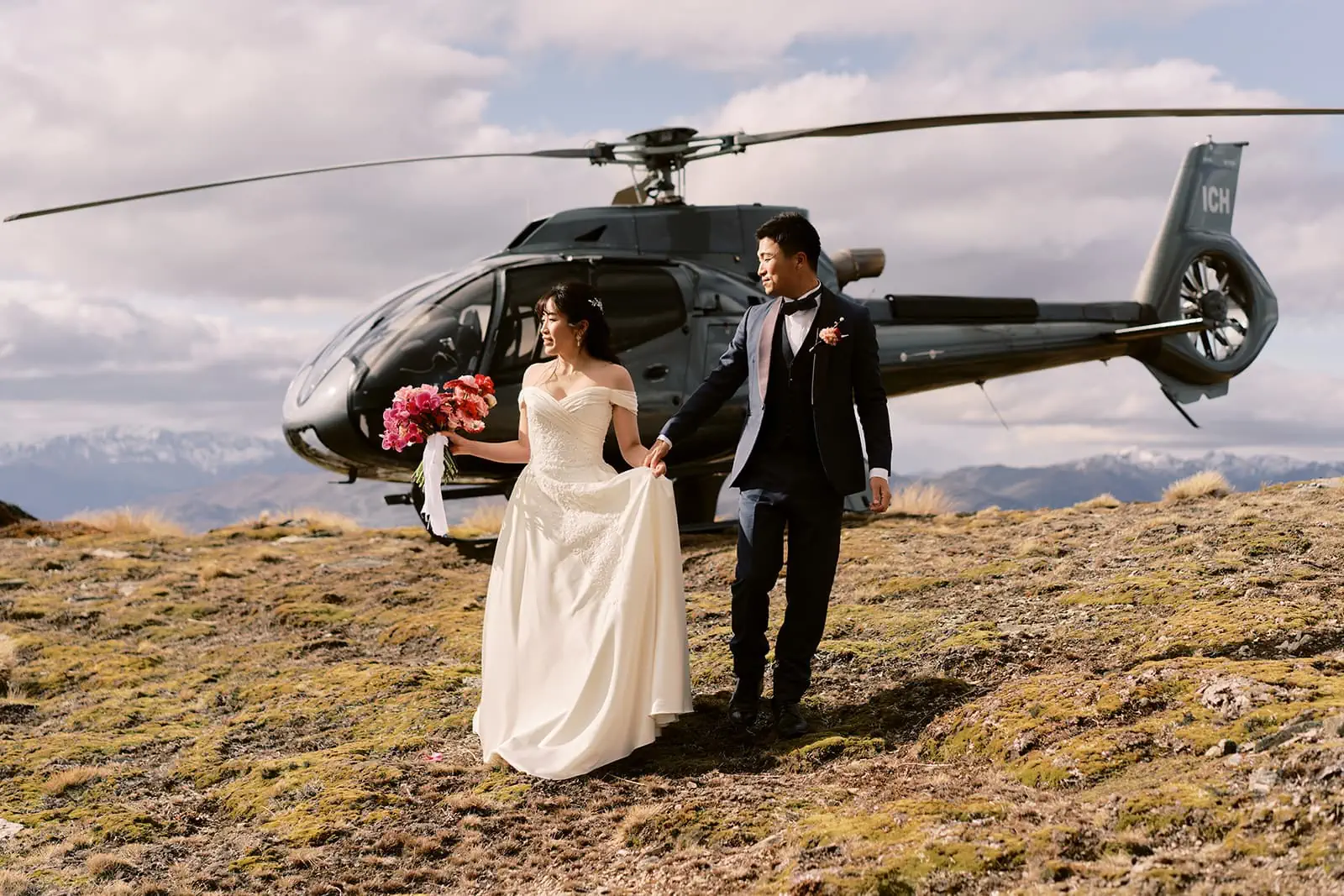 Queenstown Elopement Heli Wedding Photographer クイーンズタウン結婚式 | A pre-wedding photoshoot captures a bride and groom standing in front of a helicopter.