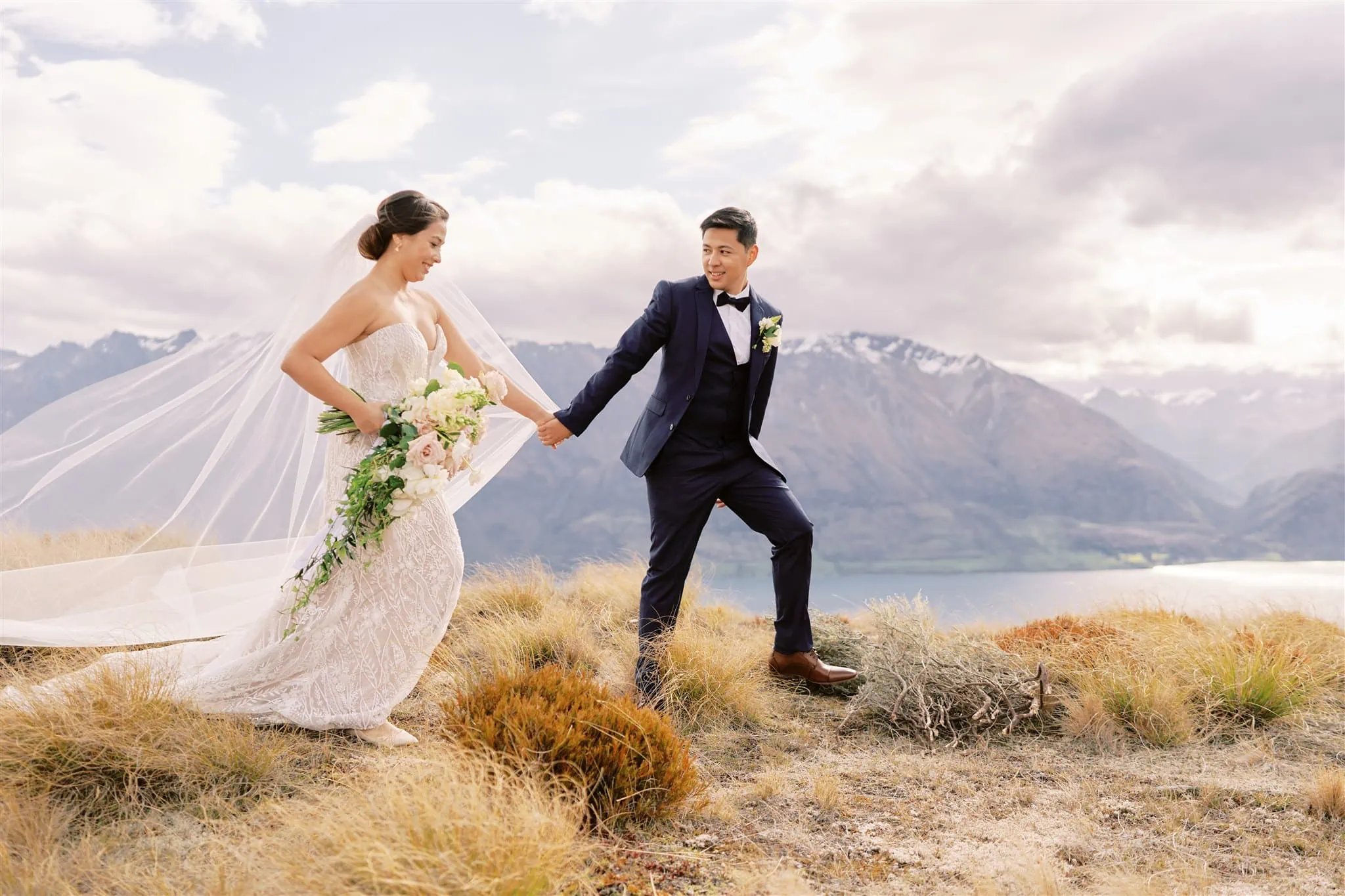 Queenstown Elopement Heli Wedding Photographer クイーンズタウン結婚式 | Mariah and her groom walking on top of a cliff in Queenstown, New Zealand.