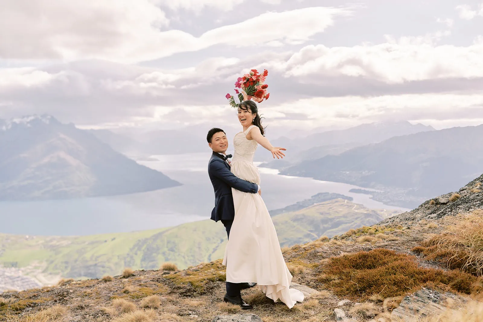 Queenstown Elopement Heli Wedding Photographer クイーンズタウン結婚式 | A pre-wedding photoshoot of a bride and groom standing on top of a mountain in Queenstown, New Zealand.
