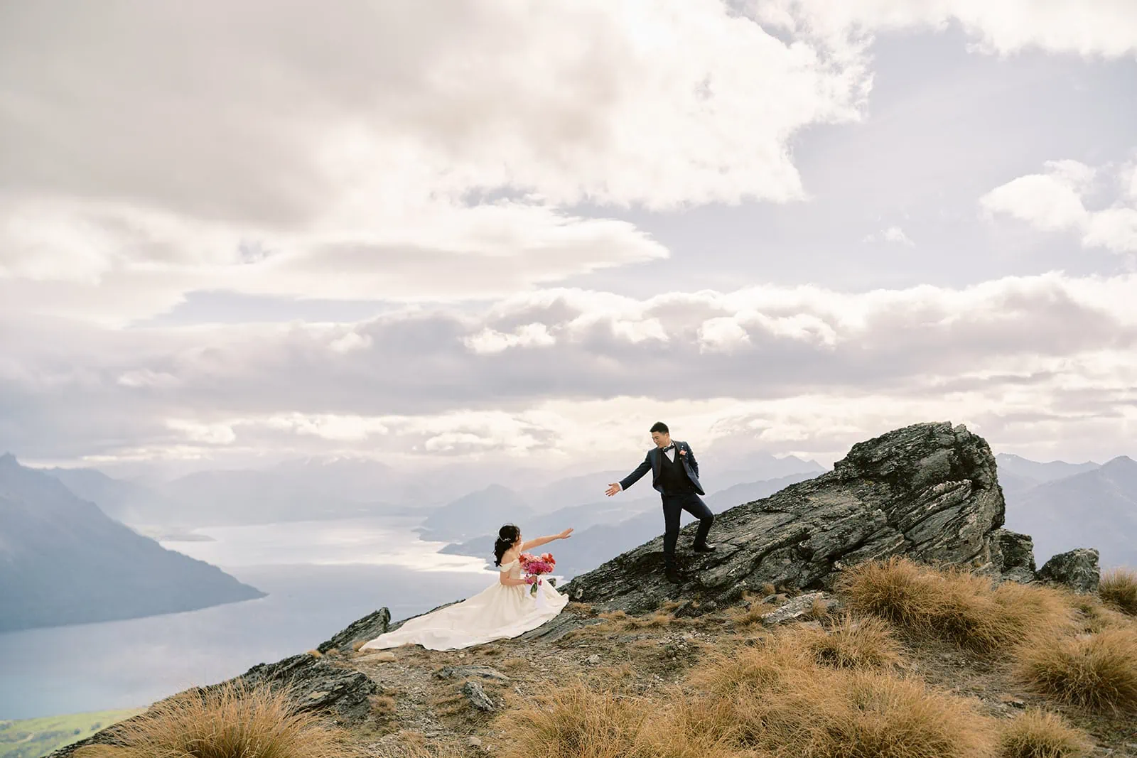 Queenstown Elopement Heli Wedding Photographer クイーンズタウン結婚式 | A couple in their pre-wedding photoshoot, standing on top of a majestic mountain in New Zealand.