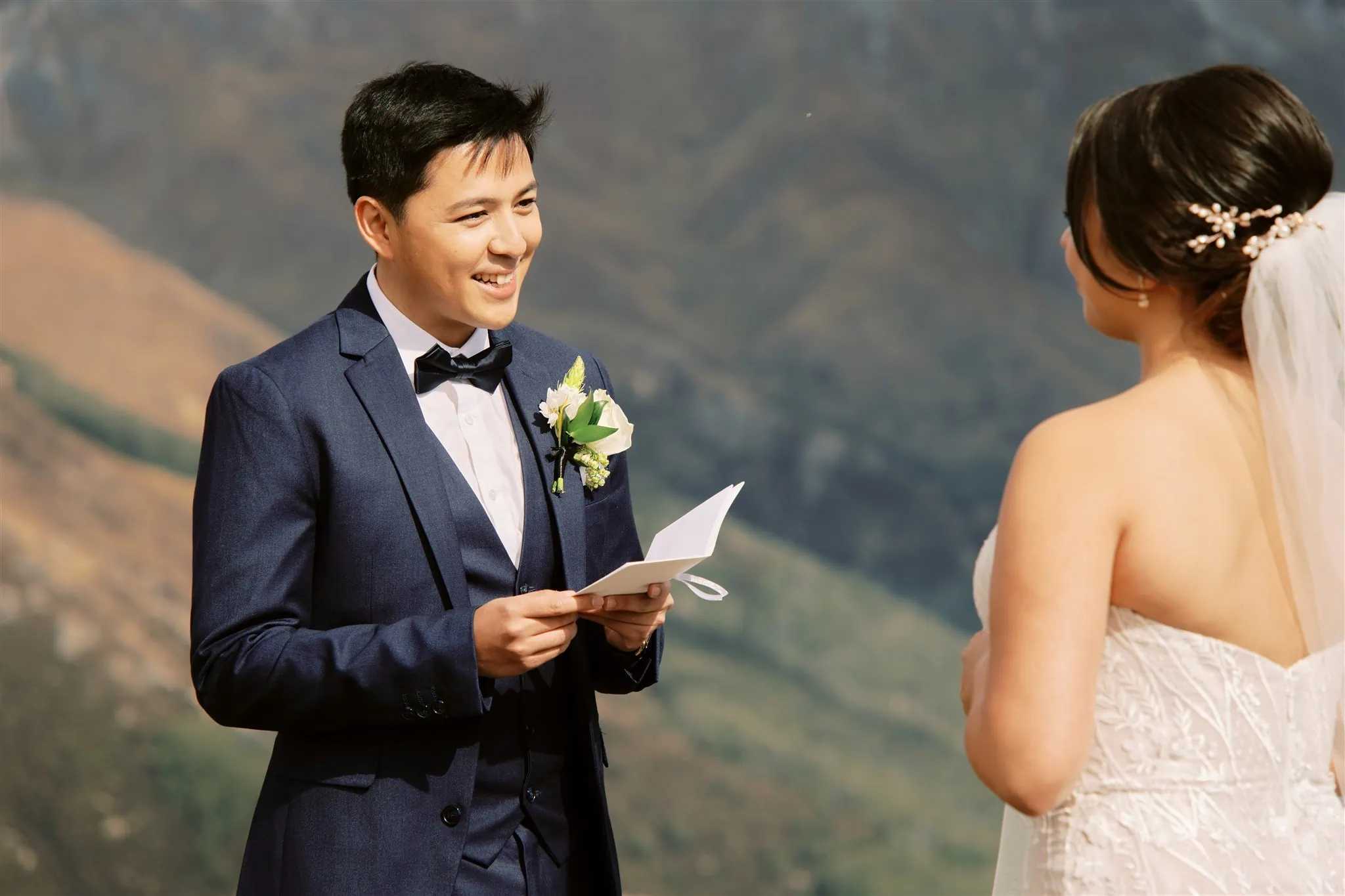 Queenstown Elopement Heli Wedding Photographer クイーンズタウン結婚式 | A Queenstown elopement takes the bride and groom on an epic journey, exchanging heartfelt vows as they stand in front of a majestic mountain. Perched on a cliff, their love for