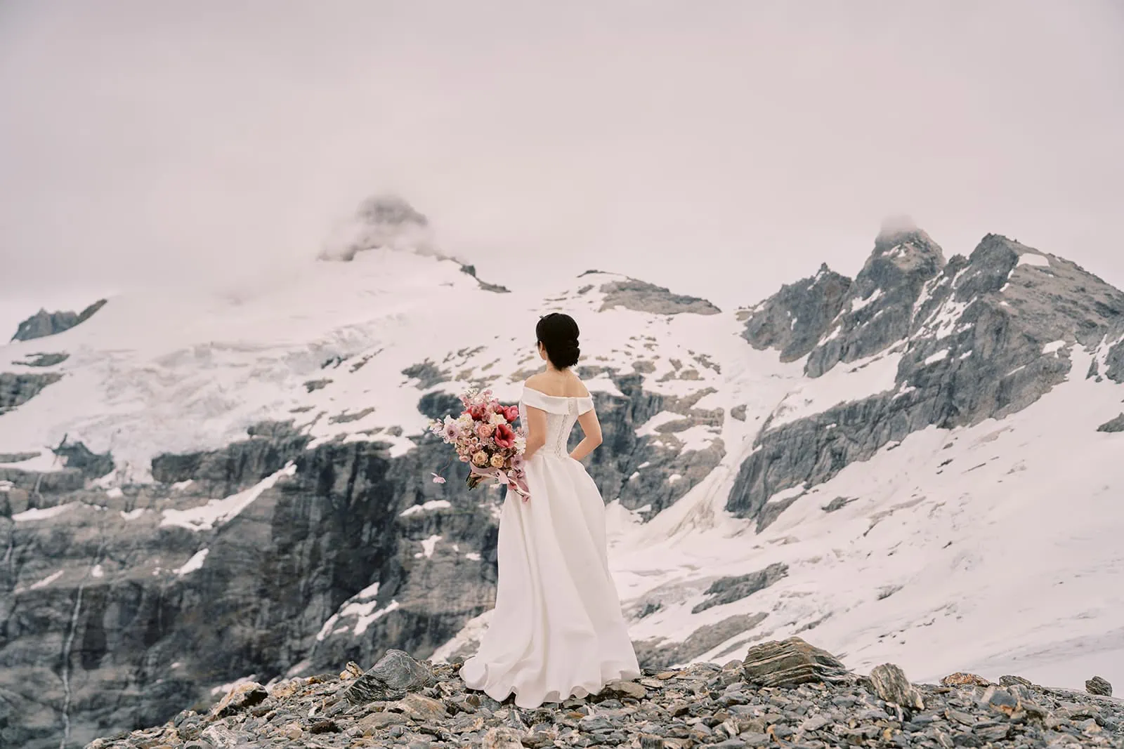 Queenstown Elopement Heli Wedding Photographer クイーンズタウン結婚式 | A bride standing on top of a mountain with a bouquet during her Queenstown Heli Elopement.