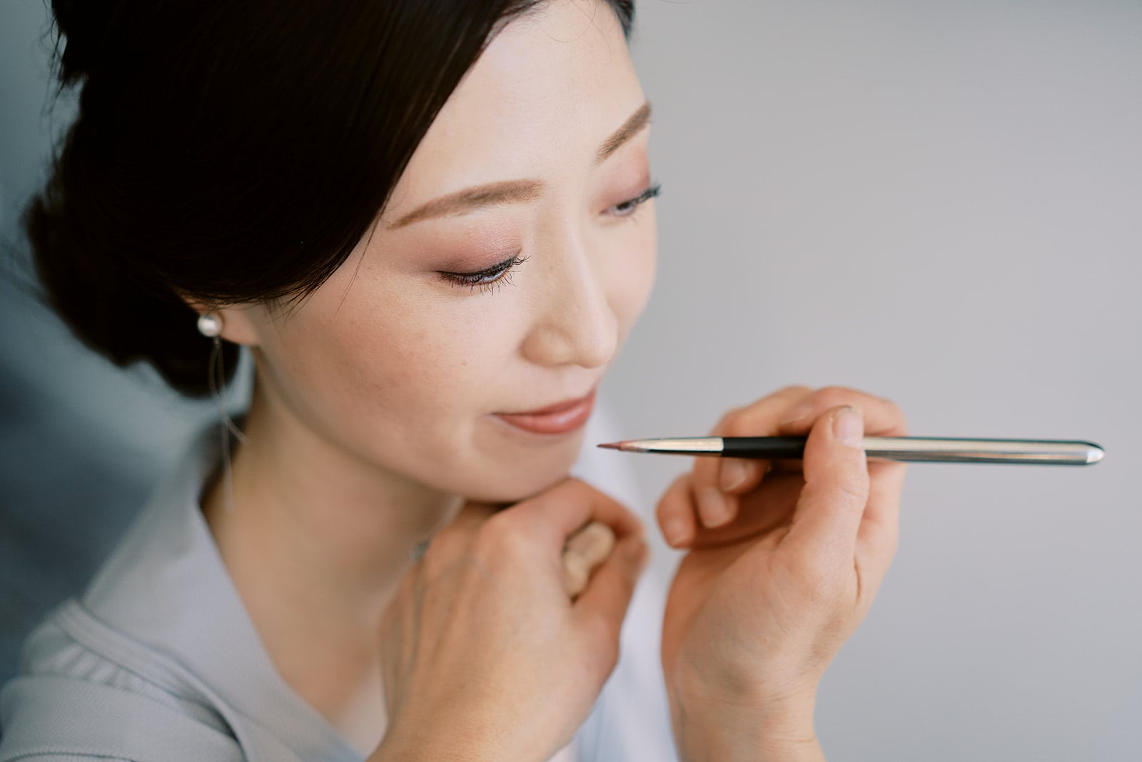 クイーンズタウン　テカポ　ニュージーランド　エロープメント 前撮り　フォトウェディング　結婚式 | 焦点が合った柔らかい背景で、思慮深く顎の近くにペンを持ち、思慮深い表情を浮かべている女性。