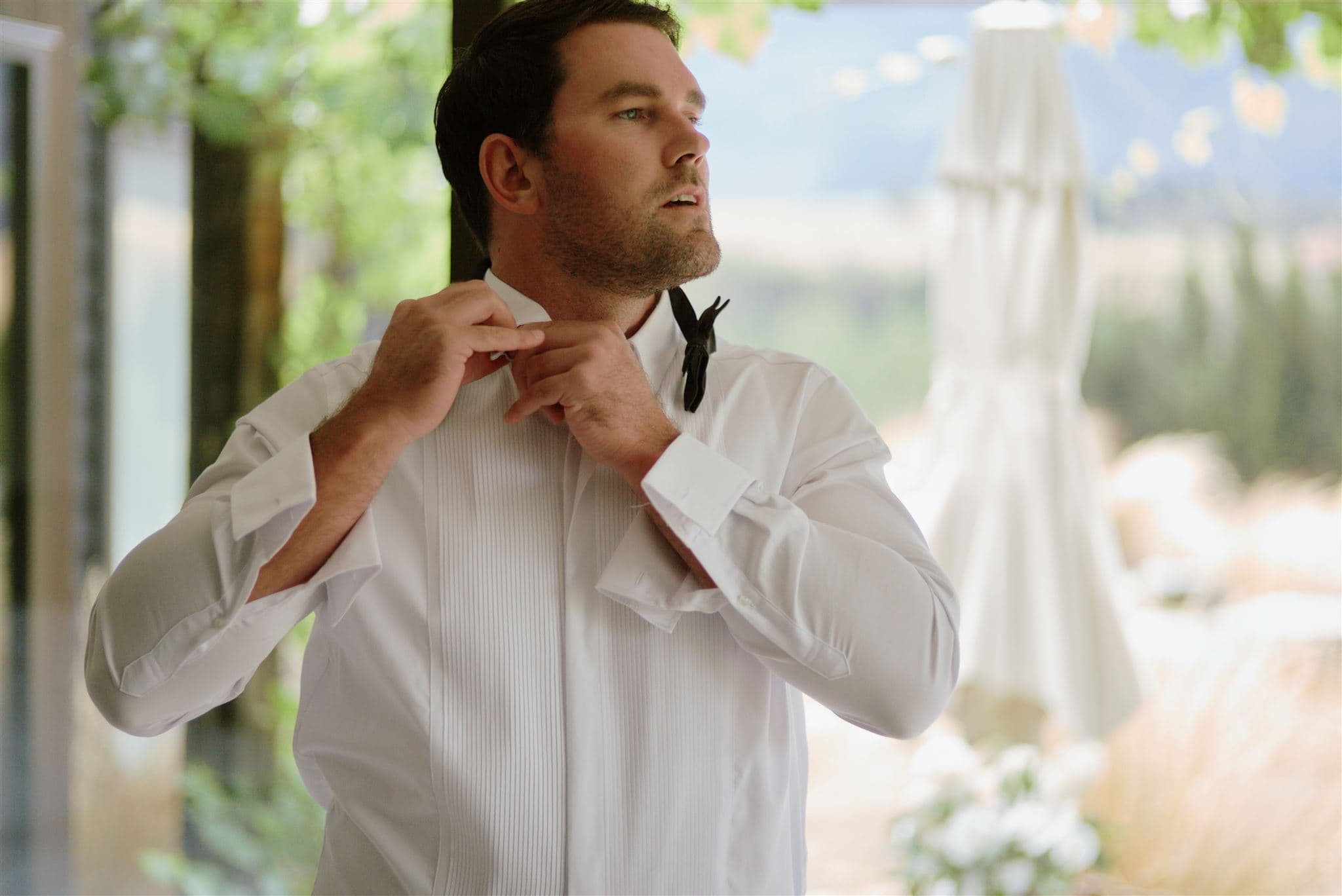 クイーンズタウン　テカポ　ニュージーランド　エロープメント 前撮り　フォトウェディング　結婚式 | 結婚式で、ぼやけた彫刻を背景に蝶ネクタイを直している男性。