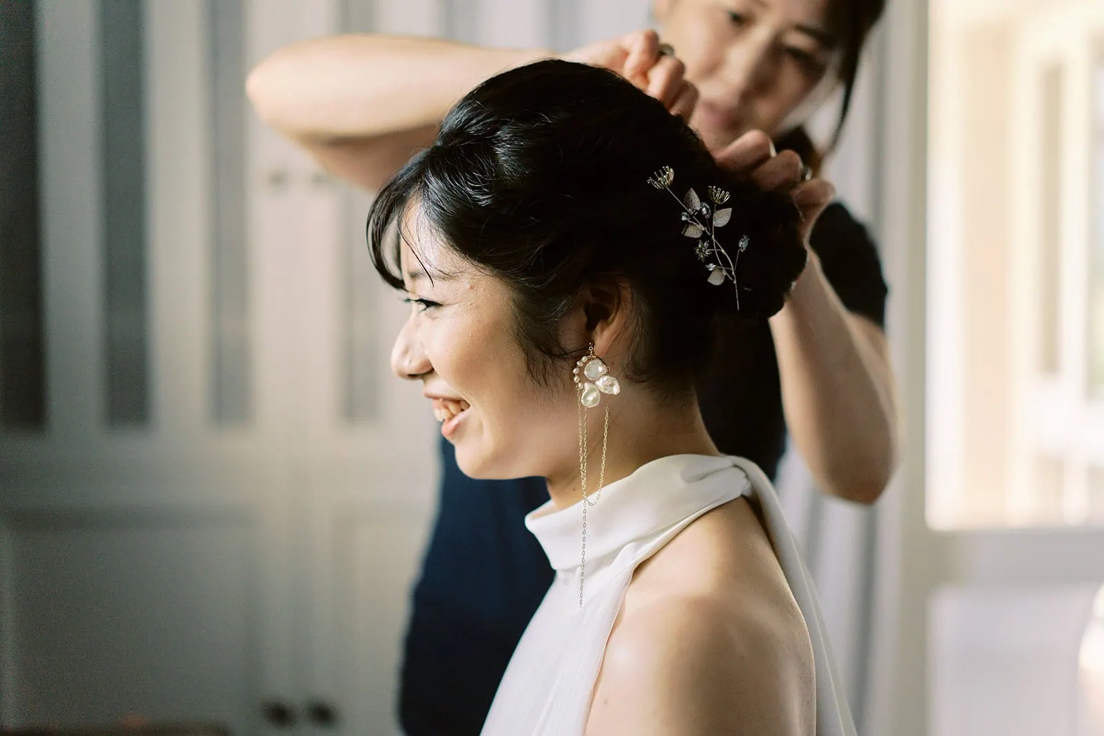 queenstown new zealand heli wedding elopement photographer videographer | A woman in a wedding dress smiling as another woman adjusts her hair accessory during their Queenstown pre-wedding shoot.