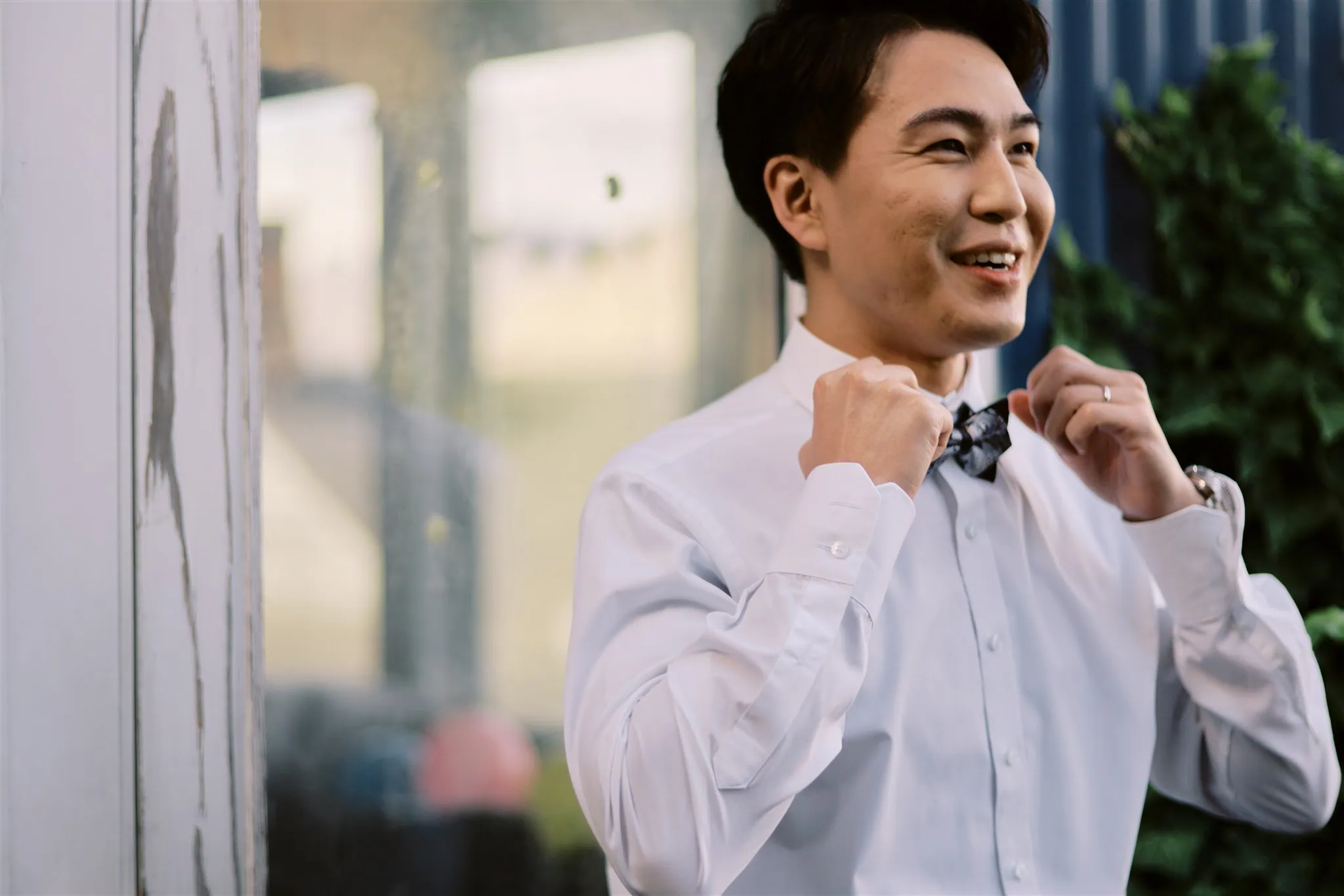 queenstown new zealand heli wedding elopement photographer videographer | Young man in a white shirt smiling and adjusting his bow tie outdoors in Queenstown.