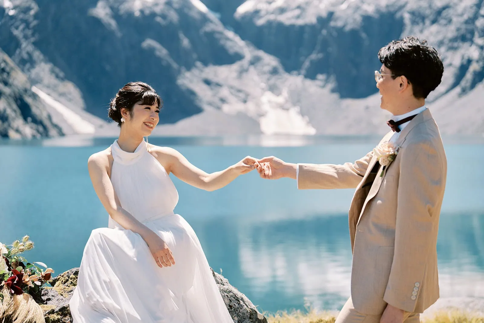 queenstown new zealand heli wedding elopement photographer videographer | A bride and groom holding hands with a serene mountain lake in the background during their Queenstown pre-wedding shoot.