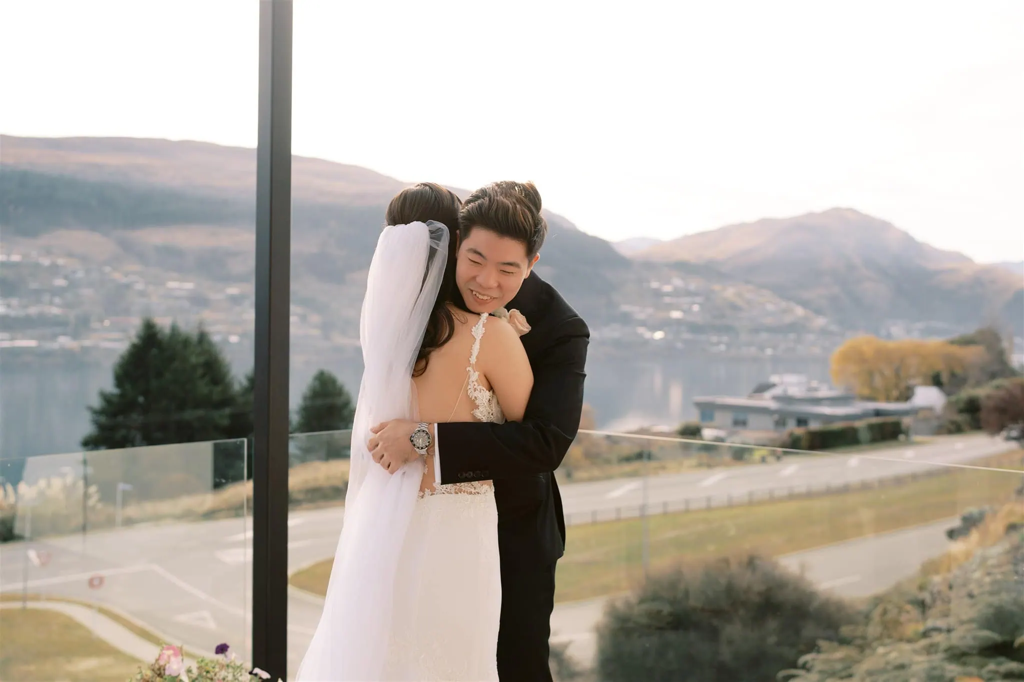 queenstown new zealand heli wedding elopement photographer videographer | A bride and groom embrace amidst the breathtaking beauty of Queenstown, with majestic mountains and a serene lake as their backdrop, capturing the essence of intimate elopement wedding photography.