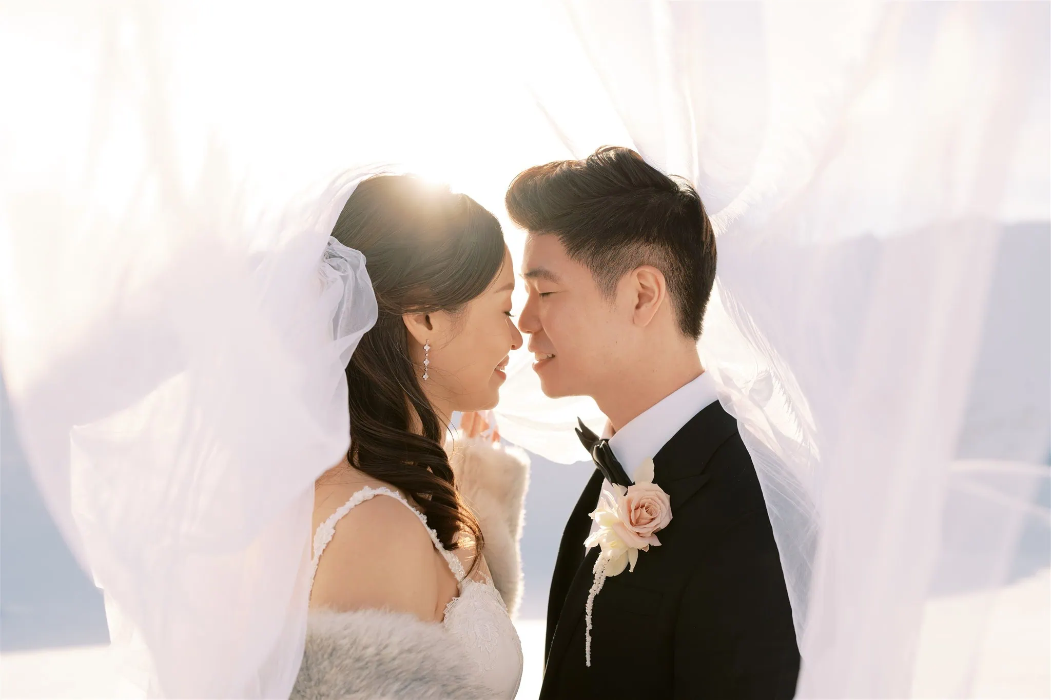 queenstown new zealand heli wedding elopement photographer videographer | A bride and groom stand closely under a flowing veil, smiling at each other with sunlight in the background, capturing the perfect moment for their Queenstown elopement.