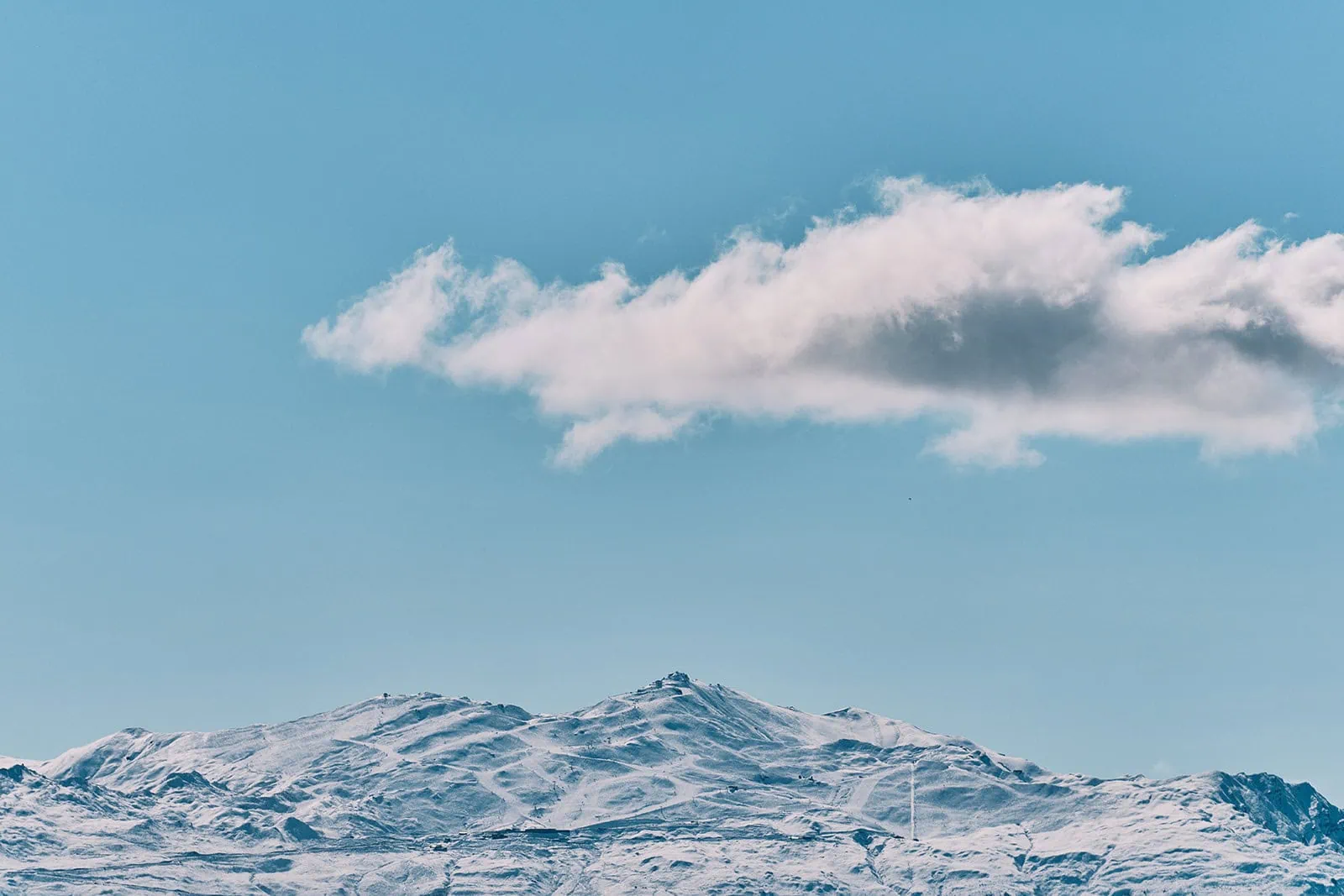 queenstown new zealand heli wedding elopement photographer videographer | Snow-covered mountain range under a clear blue sky with a single white cloud hovering above the peaks, overlooking scenic Jacks Point near Queenstown—an ideal AirBnB getaway.
