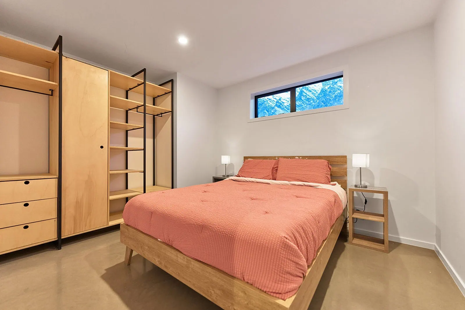 queenstown new zealand heli wedding elopement photographer videographer | A minimalist bedroom in Jacks Point, Queenstown, featuring a double bed with a rust-colored duvet, two bedside tables with lamps, a large wooden wardrobe, and a small window—perfect for your AirBnB stay.